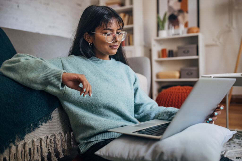 isurely reclined, a woman with stylish glasses uses a laptop in the comfort of her contemporary living area